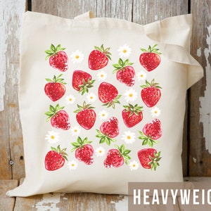 May include: A white canvas tote bag with a red strawberry and white daisy pattern. The bag is labeled "HEAVYWEIGHT" in brown text.