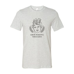 May include: A heather grey t-shirt with a black line drawing of a person with leaves growing from their head. The text "GROW POSITIVE THOUGHTS" is printed below the drawing.