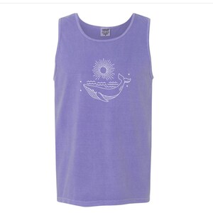 K&ouml;nnte beinhalten: Ein lilafarbenes Tanktop mit einer wei&szlig;en Umrandung eines Wals, der aus dem Wasser springt, mit einer Sonne und Sternen im Hintergrund.