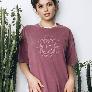 Puede incluir: Una camiseta de gran tama&ntilde;o de color malva con un gr&aacute;fico blanco de una luna creciente y estrellas con rayos de sol. El texto "Berry" est&aacute; impreso debajo del gr&aacute;fico.