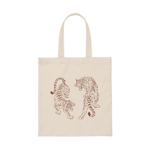 May include: A beige tote bag with two brown line drawings of tigers facing each other.