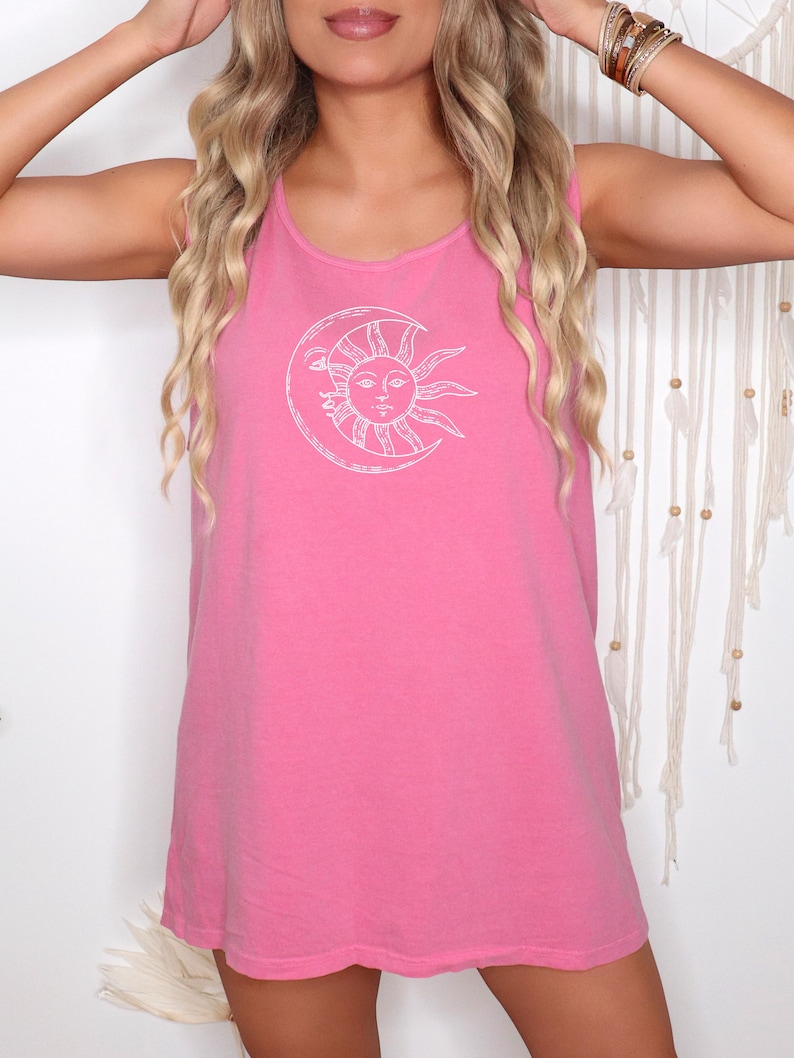 May include: A sleeveless pink tank top with a white sun and moon graphic. The sun has a face and rays, and the moon is a crescent shape. The top is made of a soft material and has a relaxed fit.