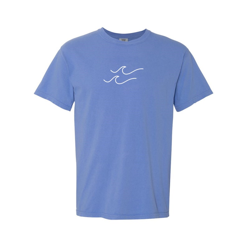 May include: A light blue t-shirt with a white wave design on the front.