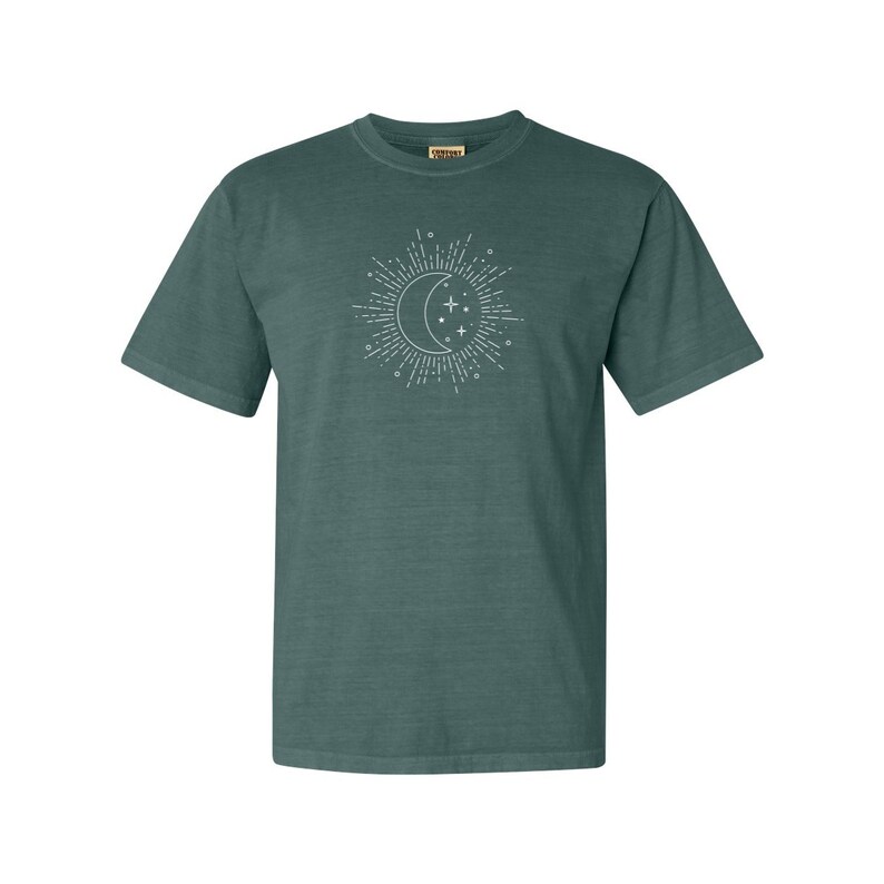 Puede incluir: Una camiseta de manga corta azul turquesa con un gr&aacute;fico blanco de una luna creciente y estrellas.