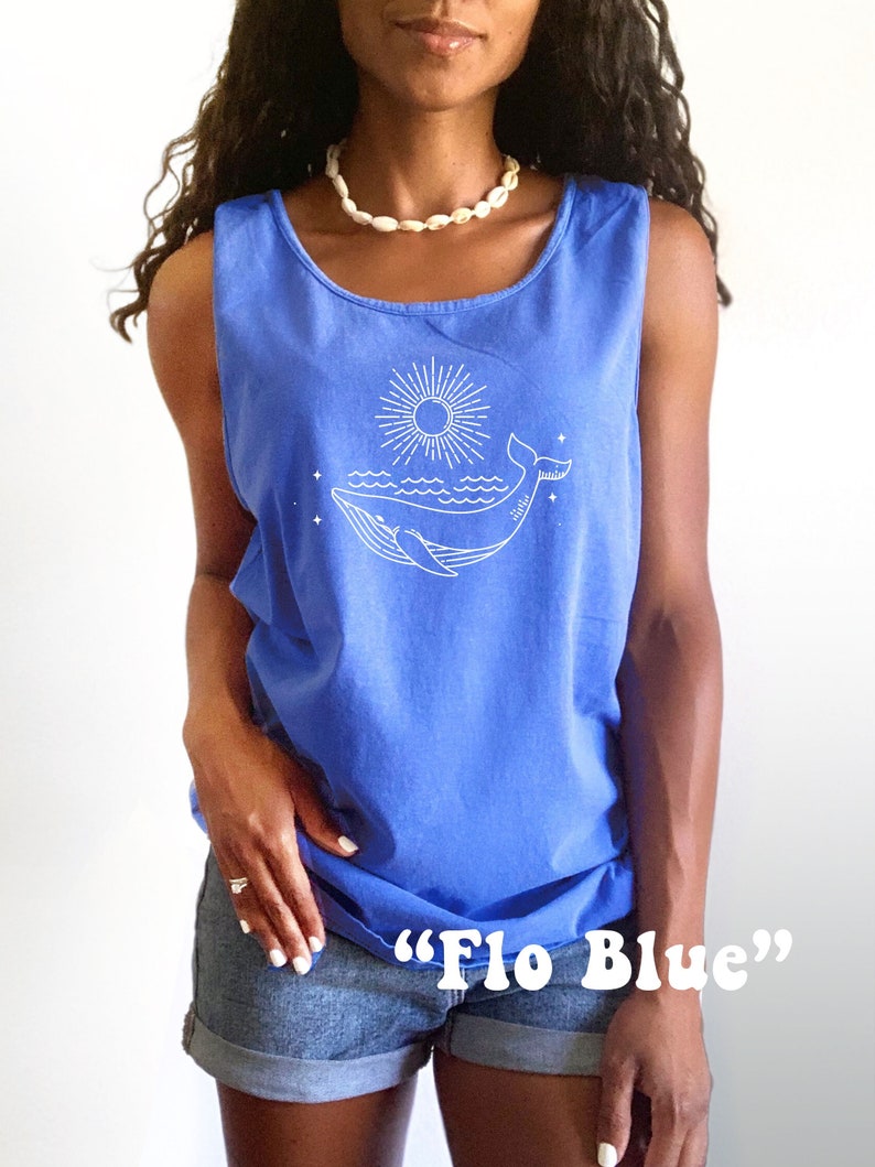 K&ouml;nnte beinhalten: Ein blaues Tanktop mit einem wei&szlig;en Wal- und Sonnenmotiv. Der Text "Flo Blue" ist auf der Unterseite des Shirts aufgedruckt.