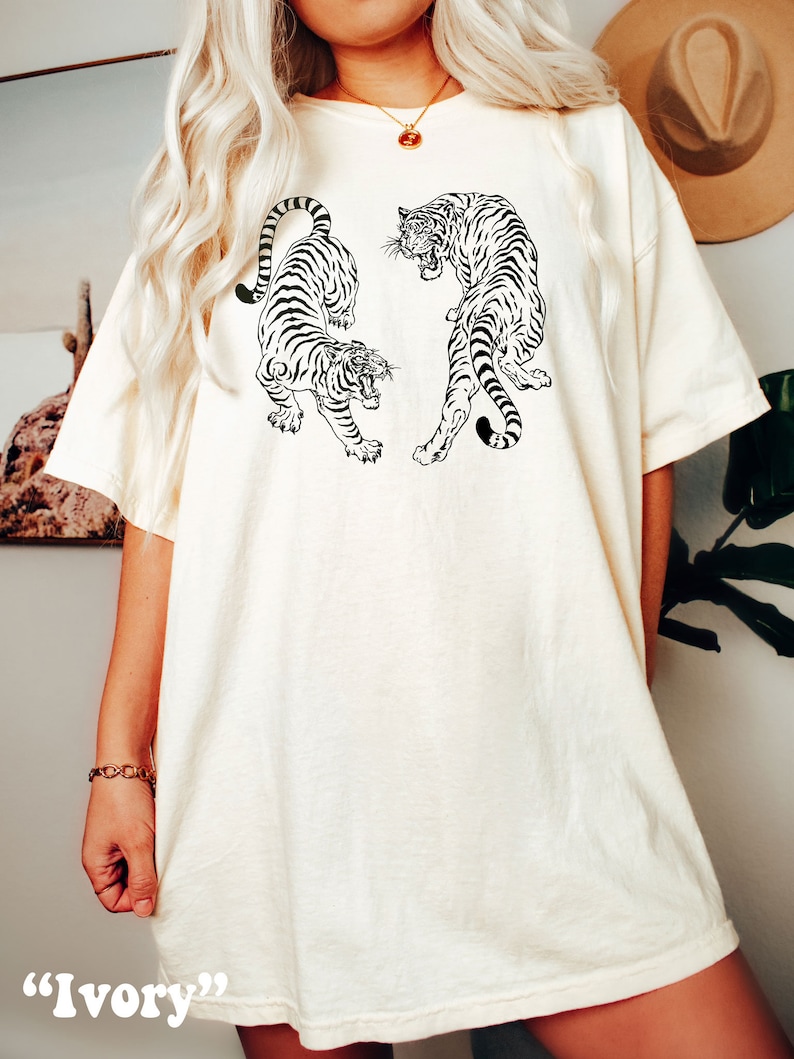 May include: A white oversized t-shirt with a black and white graphic of two tigers facing each other. The text "Ivory" is written below the image.