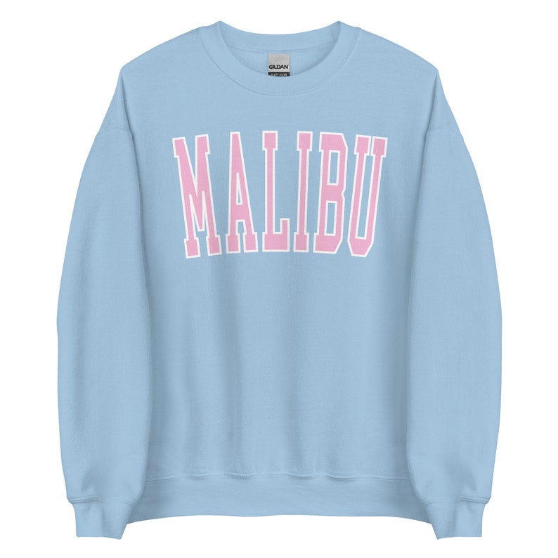 K&ouml;nnte beinhalten: Ein hellblauer Pullover mit dem Wort "MALIBU" in rosa Buchstaben.