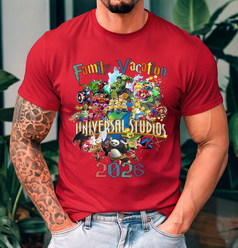 Op de afbeelding: Rood t-shirt met een kleurrijke afbeelding met verschillende stripfiguren en de tekst "Family Vacation Universal Studios 2026". Het ontwerp bevat personages van Marvel, Nintendo en andere populaire franchises.