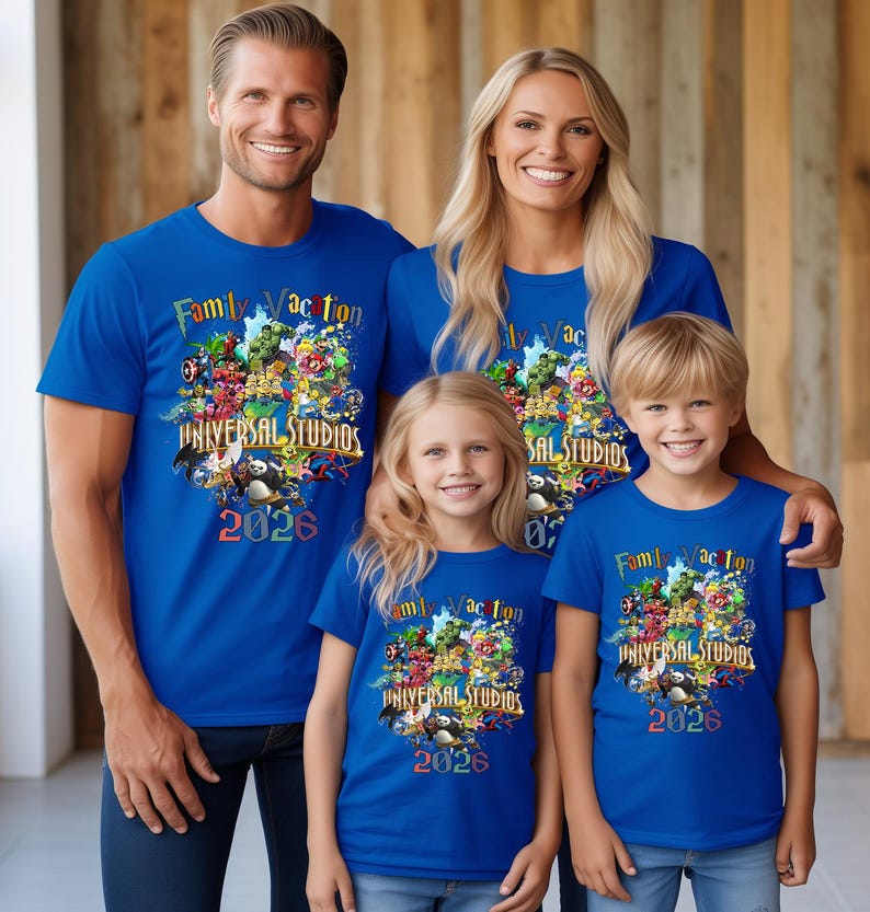 Op de afbeelding: Vier mensen dragen bijpassende blauwe t-shirts met de tekst "Family Vacation UNIVERSAL STUDIOS 2026" en een kleurrijke afbeelding. De shirts hebben korte mouwen en de familie lacht.