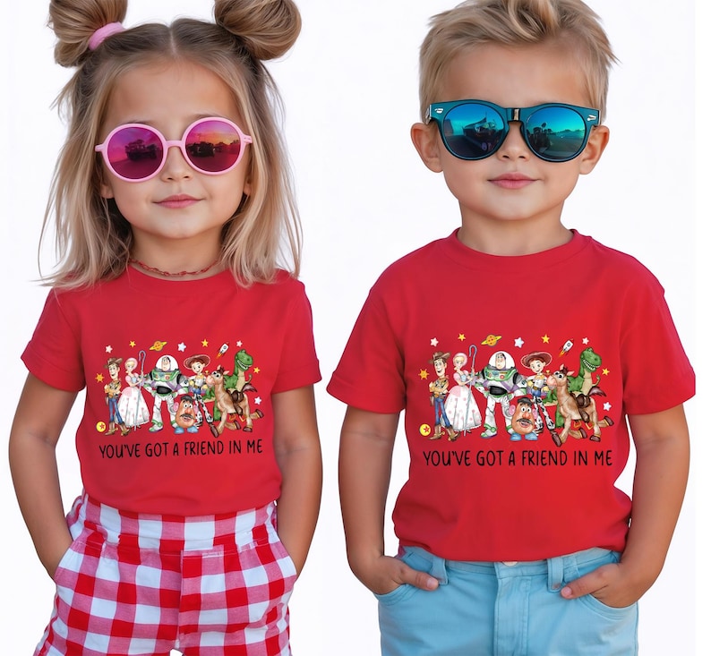May include: Two children wearing red t-shirts with a colorful graphic of animated characters and the text "YOU'VE GOT A FRIEND IN ME". The girl wears pink sunglasses and the boy wears blue sunglasses.