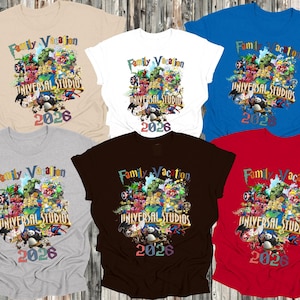 Op de afbeelding: T-shirts in diverse kleuren met de tekst "Family Vacation UNIVERSAL STUDIOS 2026" en een ontwerp met stripfiguren. De shirts zijn beige, wit, blauw, grijs, bruin en rood.