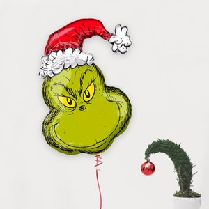 Pu&ograve; includere: Pallone verde del Grinch con un cappello di Babbo Natale rosso e bianco. Il pallone &egrave; legato a una corda e c'&egrave; un piccolo ornamento rosso appeso a un cespuglio verde.