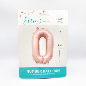 May include: Rose gold number 0 balloon, 32 inches (81 cm) in size.  The balloon is packaged in a clear plastic bag with a white and pink label that says "Ellie's Brand" and "Number Balloon".