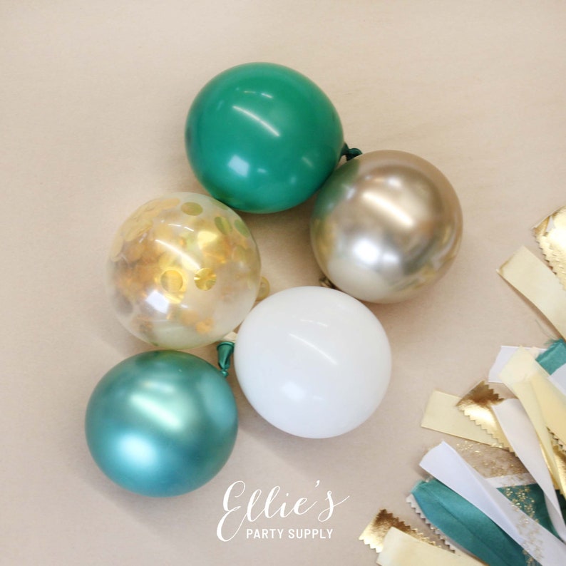 Op de afbeelding: Een groep ballonnen in de kleuren groen, goud en wit. De ballonnen zijn gerangschikt in een cluster op een beige oppervlak. De ballonnen zijn een mix van effen kleuren en confetti-gevulde ballonnen.