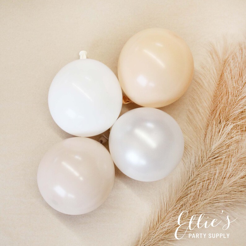 May include: Four balloons in various shades of beige, white, and cream. The balloons are arranged in a semi-circle on a light brown background.