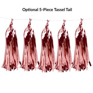 May include: Five rose gold tassel tails hanging from a string. The tassels are made of shiny, metallic material and are arranged in a row. The text "Optional 5-Piece Tassel Tail" is above the tassels.