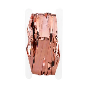 May include: A roll of rose gold metallic streamer for party decorations. The streamer is made of thin, shiny strips of foil.
