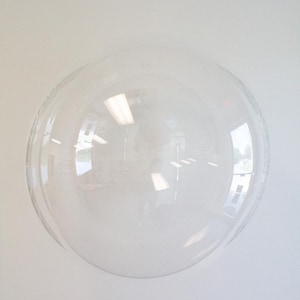 Op de afbeelding: Een grote, ronde, transparante ballon. De ballon is opgeblazen en lijkt gemaakt te zijn van een duurzaam kunststofmateriaal.
