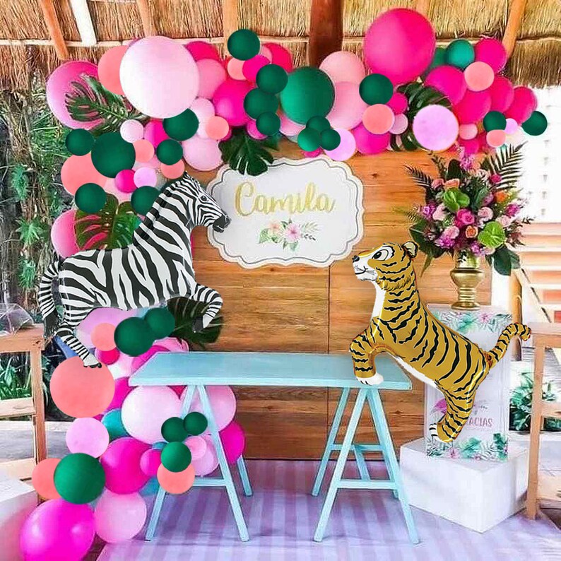May include: A jungle-themed party decoration with pink, green, and white balloons, a zebra and tiger balloon animal, and a sign that says "Camila".