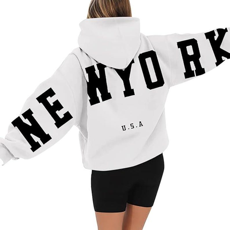 May include: White hooded sweatshirt with black lettering that says "NEW YORK" on the back and "U.S.A" on the front.