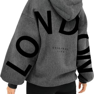 May include: Gray hooded sweatshirt with the word "LONDON" printed in black on the back. The text "ORIGINAL LIFE" is printed in smaller letters below the word "LONDON".