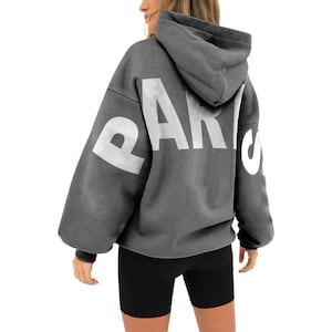 May include: A gray hooded sweatshirt with the word "PARIS" printed in white on the back. The sweatshirt has a relaxed fit and a drawstring hood.