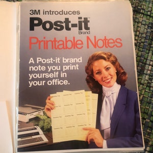 May include: A woman in a blue blazer holds up several yellow Post-it Brand Printable Notes. The notes have the words "Inventory Tag" printed on them. The text on the ad reads "3M introduces Post-it Brand Printable Notes. A Post-it brand note you print yourself in your office."