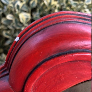 Puede incluir: Primer plano del borde superior de un marco de madera rojo con un borde dorado. El marco tiene un borde decorativo festoneado.