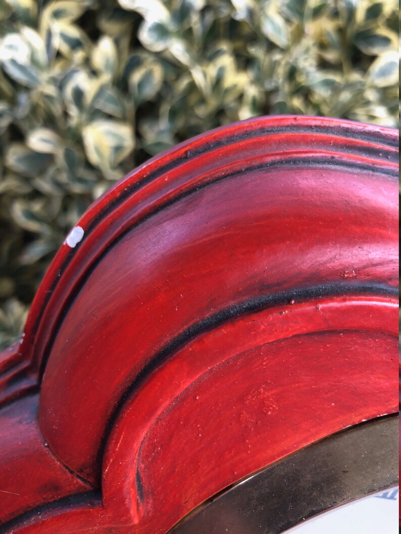 Puede incluir: Primer plano del borde superior de un marco de madera rojo con un borde dorado. El marco tiene un borde decorativo festoneado.