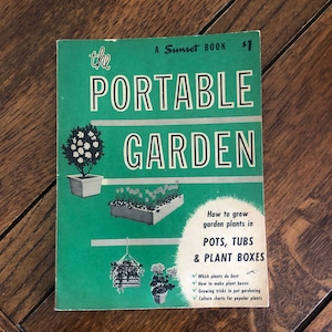 May include: A green book titled "The Portable Garden: How to grow garden plants in pots, tubs & plant boxes". The book cover features illustrations of potted plants and a small gardening trowel.