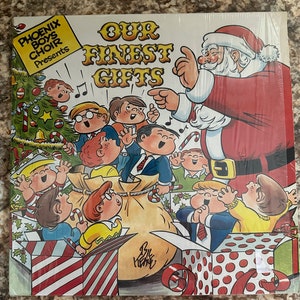 May include: A vintage Christmas record album cover featuring a cartoon Santa Claus pointing to a group of children singing carols. The album is titled "Our Finest Gifts" and is presented by the Phoenix Boys Choir.