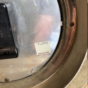Puede incluir: La parte posterior de un reloj redondo plateado con un anillo exterior marr&oacute;n. El reloj tiene una pegatina que dice "TICK TOCK SHOP (403) 425-8585" y un n&uacute;mero escrito a mano "7086.2".