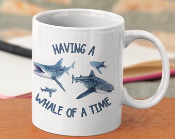May include: White ceramic mug with a blue whale shark design and the text "HAVING A WHALE OF A TIME".