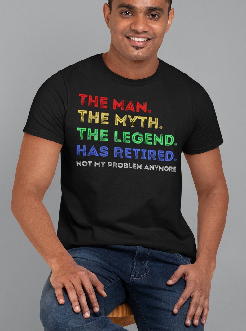 May include: A black t-shirt with a rainbow coloured graphic that reads "THE MAN. THE MYTH. THE LEGEND. HAS RETIRED. NOT MY PROBLEM ANYMORE."