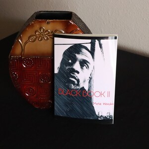 K&ouml;nnte beinhalten: Ein Schwarzwei&szlig;foto einer Person auf dem Cover eines Buches mit dem Titel "BLACK BOOK II" von Mose Hardin.