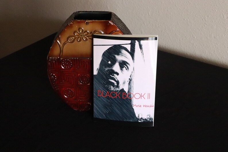 K&ouml;nnte beinhalten: Ein Schwarzwei&szlig;foto einer Person auf dem Cover eines Buches mit dem Titel "BLACK BOOK II" von Mose Hardin.