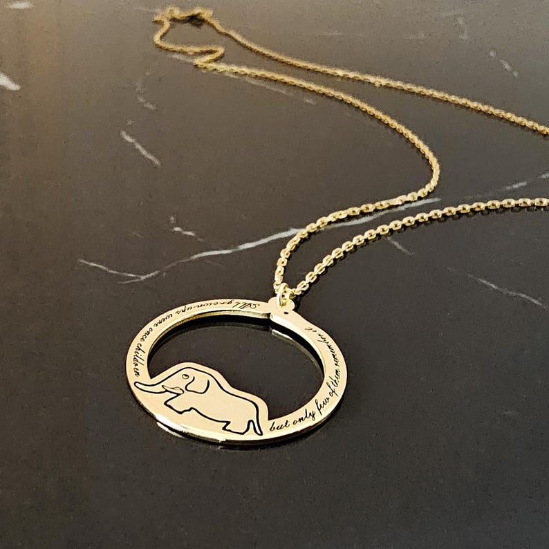 K&ouml;nnte beinhalten: Goldkette mit einem runden Anh&auml;nger, der eine Elefanten-Silhouette und die Inschrift "Ich werde dich immer in Erinnerung behalten, aber nur f&uuml;r ein paar Momente" zeigt.