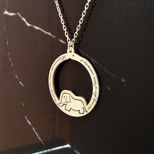 K&ouml;nnte beinhalten: Goldkette mit einem runden Anh&auml;nger, der eine Elefanten-Silhouette und die Inschrift "Erwachsene waren einst Kinder, aber nur wenige erinnern sich daran" zeigt.