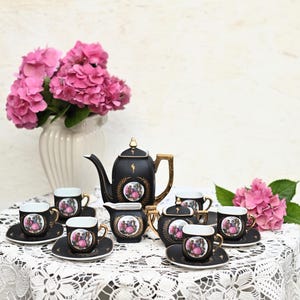 May include: A black and gold tea set with a floral design. The set includes a teapot, sugar bowl, creamer, and six teacups and saucers.