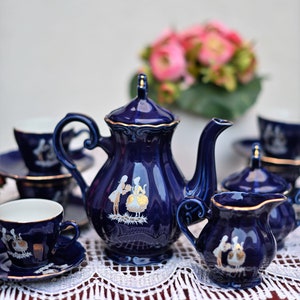 May include: A blue and gold tea set with a teapot, creamer, sugar bowl, and two cups and saucers. The set features a delicate floral design with gold accents.