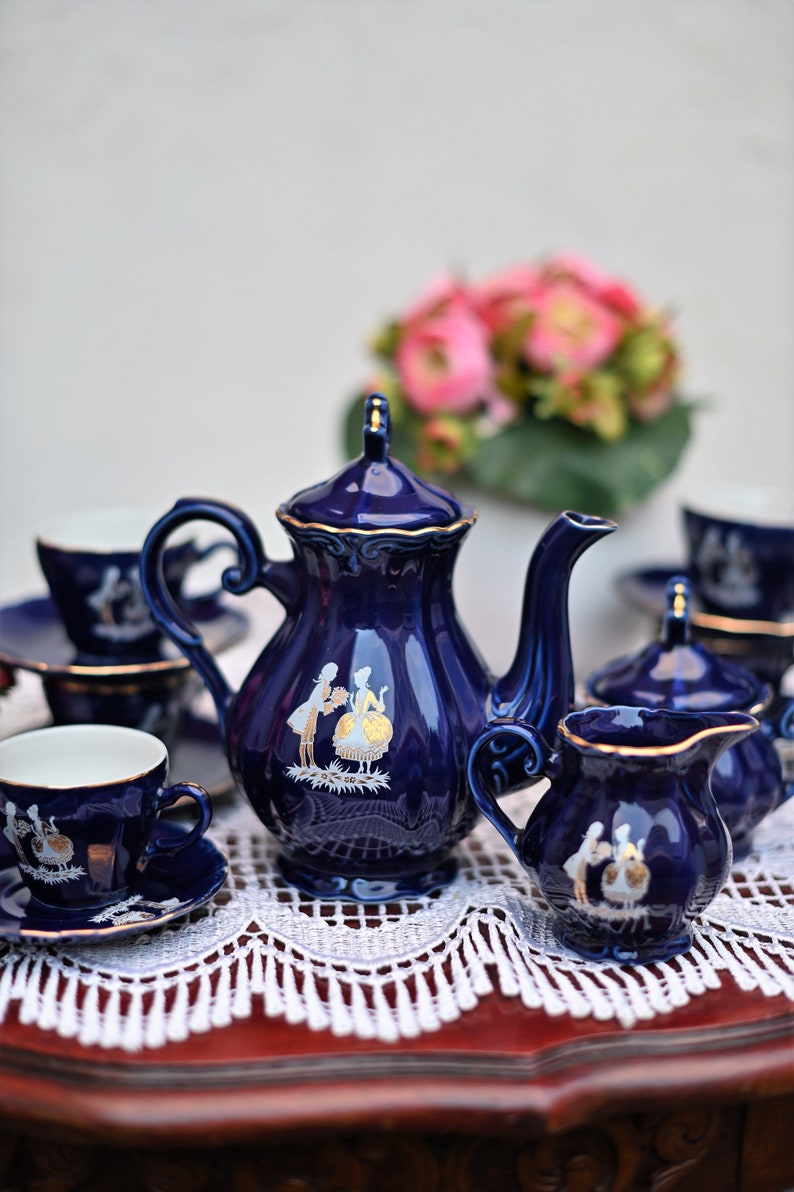 May include: A blue and gold tea set with a teapot, creamer, sugar bowl, and two cups and saucers. The set features a delicate floral design with gold accents.