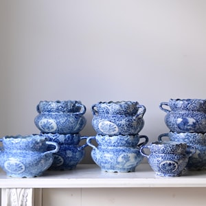 May include: A stack of blue and white ceramic planters with intricate floral designs. The planters have a scalloped rim and two handles on each side.
