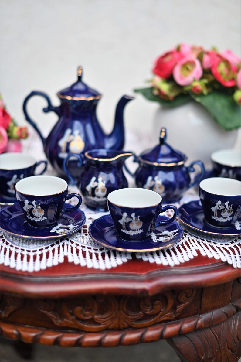 May include: A blue and white porcelain tea set with a floral design. The set includes a teapot, creamer, sugar bowl, and four teacups and saucers.