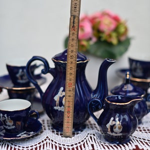 May include: A blue and gold porcelain tea set with a floral design. The set includes a teapot, creamer, sugar bowl, and two teacups and saucers.