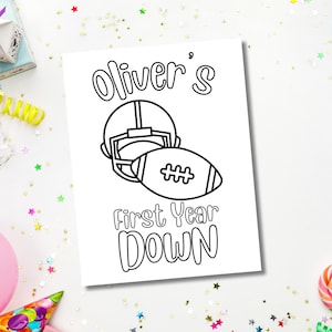 Op de afbeelding: Een zwart-witte kleurplaat met een voetbalhelm en een voetbal met de tekst "Oliver's First Year Down".