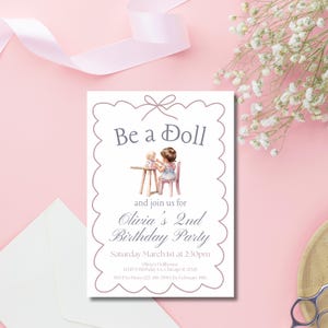 May include: A white invitation with a scalloped border and a purple bow at the top. The invitation says "Be a Doll" and has a picture of a girl playing with a doll. The text says "Olivia's 2nd Birthday Party" and includes the date, time, and location of the party. RSVP information is also included.