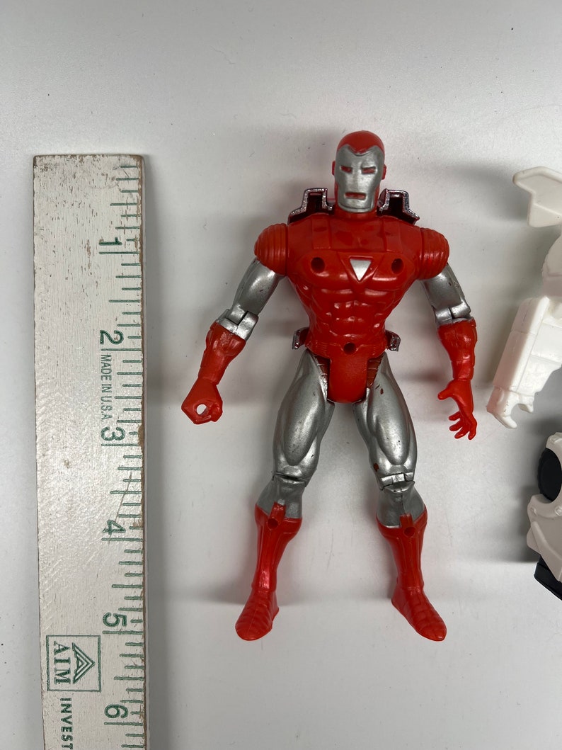 May include: Red and silver action figure of Iron Man, a superhero from Marvel Comics. The figure is approximately 5 inches tall and has a detailed sculpt.