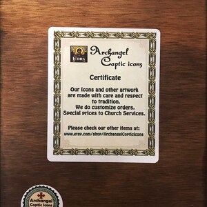Pu&ograve; includere: Una targa in legno con un certificato di Archangel Coptic Icons. Il certificato afferma che le loro icone e opere d'arte sono realizzate con cura e rispetto per la tradizione. Offrono ordini personalizzati e prezzi speciali per i servizi religiosi. Il certificato include anche un indirizzo del sito web: www.etsy.com/shop/ArchangelCopticicons.
