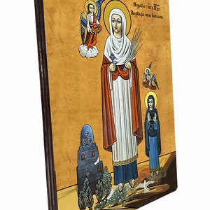 Pu&ograve; includere: Un'icona religiosa di Santa Barbara, una martire cristiana, raffigurata con una veste bianca che tiene in mano spighe di grano. L'icona &egrave; dipinta su un pannello di legno con una cornice marrone. Il testo "&Pi;&iota;&sigma;&tau;&epsilon;ύ&epsilon;&iota; &eta;&tau;&epsilon; &Pi;&iota;&sigmaf; &Beta;&alpha;&rho;&beta;ά&rho;&alpha; &eta;&epsilon;&iota; ί&omega;&alpha;.&nu;&alpha;" &egrave; scritto in greco nella parte superiore dell'icona.