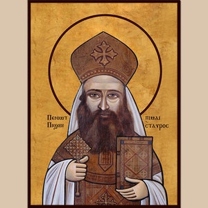 May include: An icon of Saint Peter of Alexandria, a religious figure, depicted in a traditional Byzantine style. He is wearing a white robe and a brown mitre with a cross on top. He is holding a book in his right hand and a staff with a cross in his left hand. The background is a gold colour.